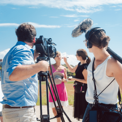 Top mistakes businesses make when hiring a corporate media team 2 A group of people with cameras outside, getting ready to interview a woman, representing corporate media team